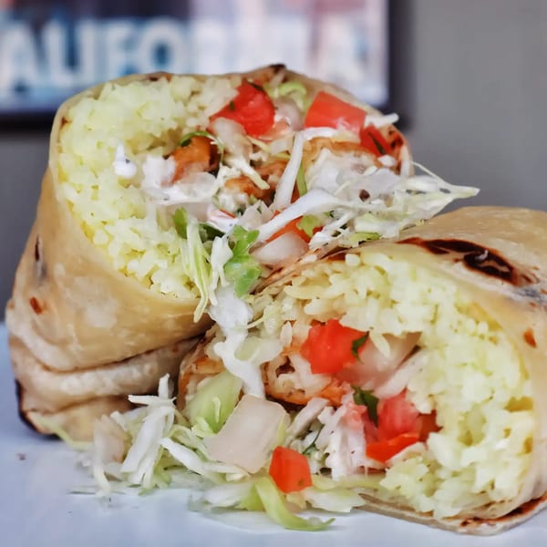 A large burrito from Elena's Taco Shop, cut in half, revealing rice, tomatoes, and shredded lettuce.