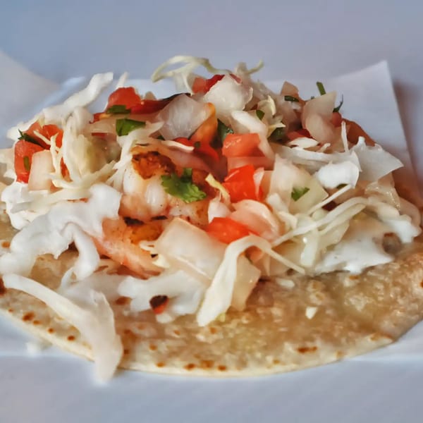 Elena's Taco Shop shrimp taco with cabbage, pico de gallo, and crema on a tortilla.
