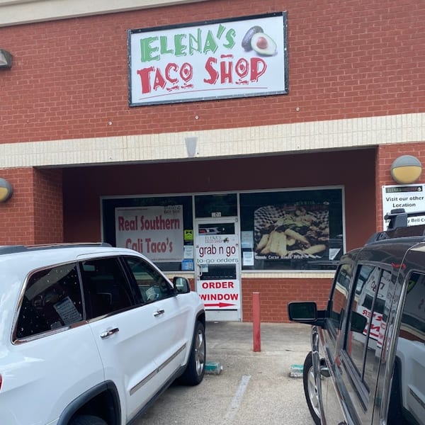 Elena's Taco Shop storefront with a drive-thru order window and two cars parked outside.